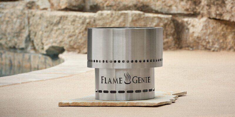 A Flame Genie stainless steel pellet fire pit sitting on a back patio by a pool.