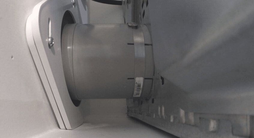 A close-up of a dryer connecting to the wall vent by way of a SnugDryer dryer vent connection kit.