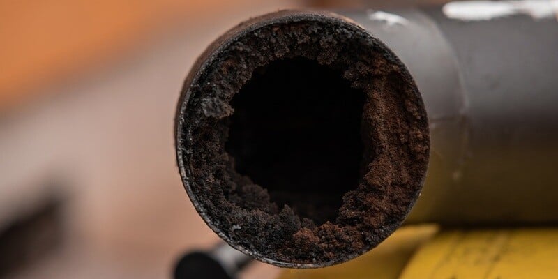 A straight-on shot of a black chimney pipe. The pipe is filled with creosote.