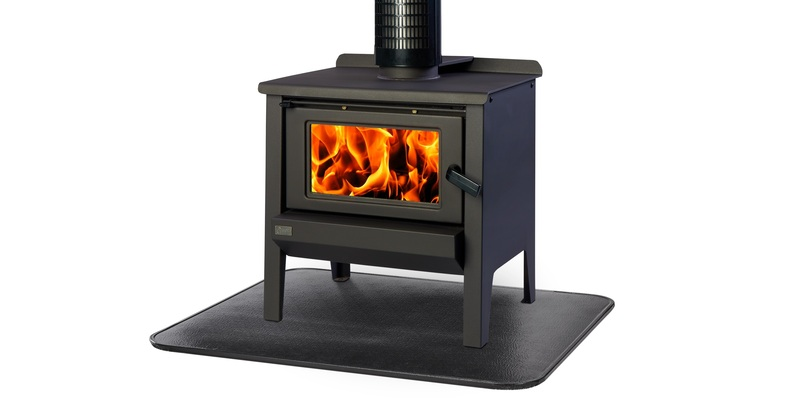 A black wood stove with a fire burning in its firebox resting on a black stove board against a white background.