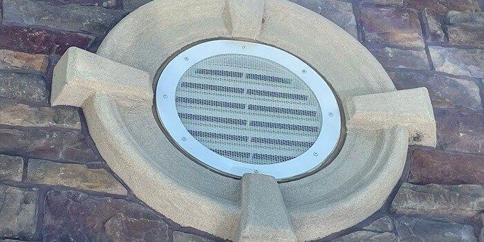 A HY-GUARD EXCLUSION Pest Armor Panel installed over a round gable end vent on a stone wall.