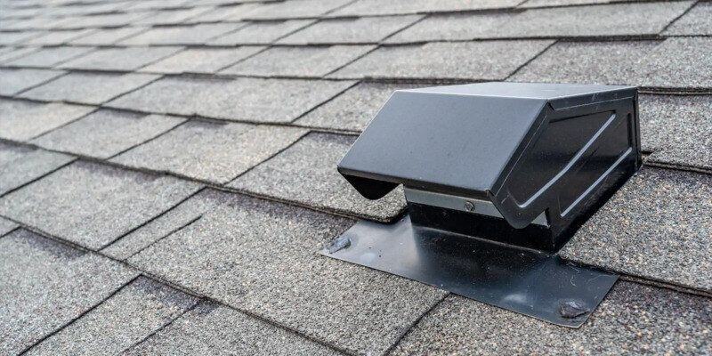 A black, hood-style roof vent on a home with dark-gray shingles.