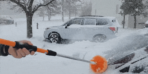 A GIF of a SpinAway rotary cleaning brush being used to clean snow off of a car on a wintry day.
