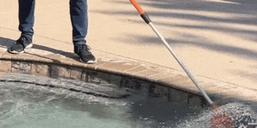 A GIF of a man using a SpinAway rotary cleaning brush to clean the walls of an in-ground pool.