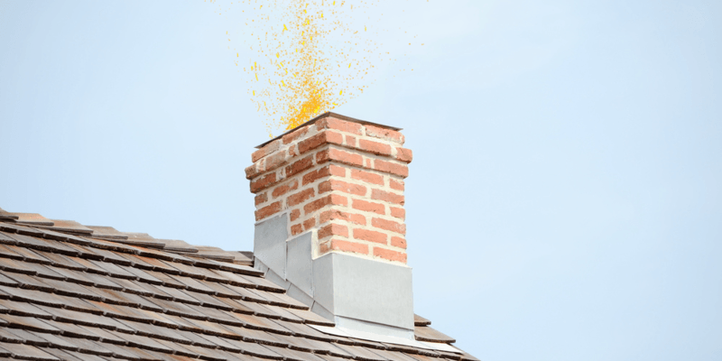 A chimney on a roof with slate shingles. Sparks are emanating from the chimney flue.