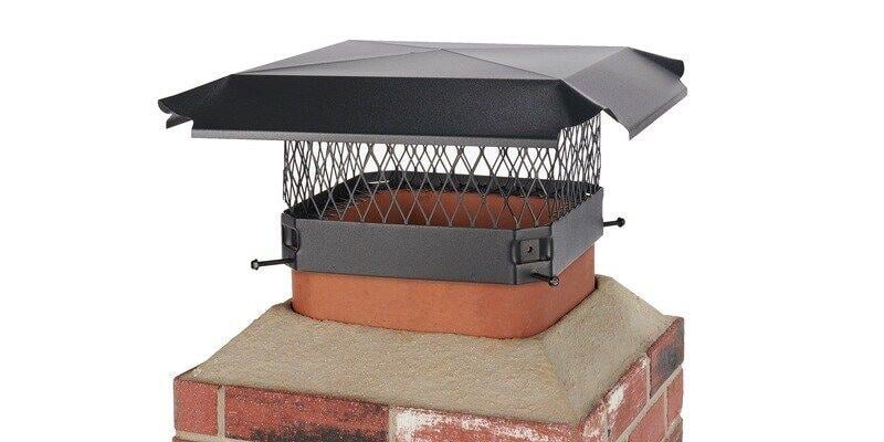A Draft King Black Galvanized Steel Chimney Cap installed on a mock chimney flue against a white background.